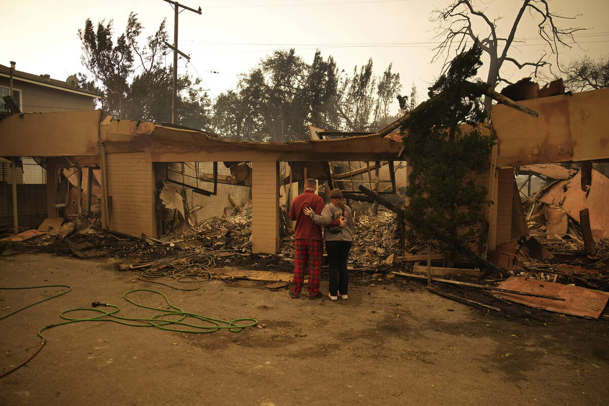 Shane Torre, left, and Stephanie Rodriguez embrace as the look at what remains of their home de ...