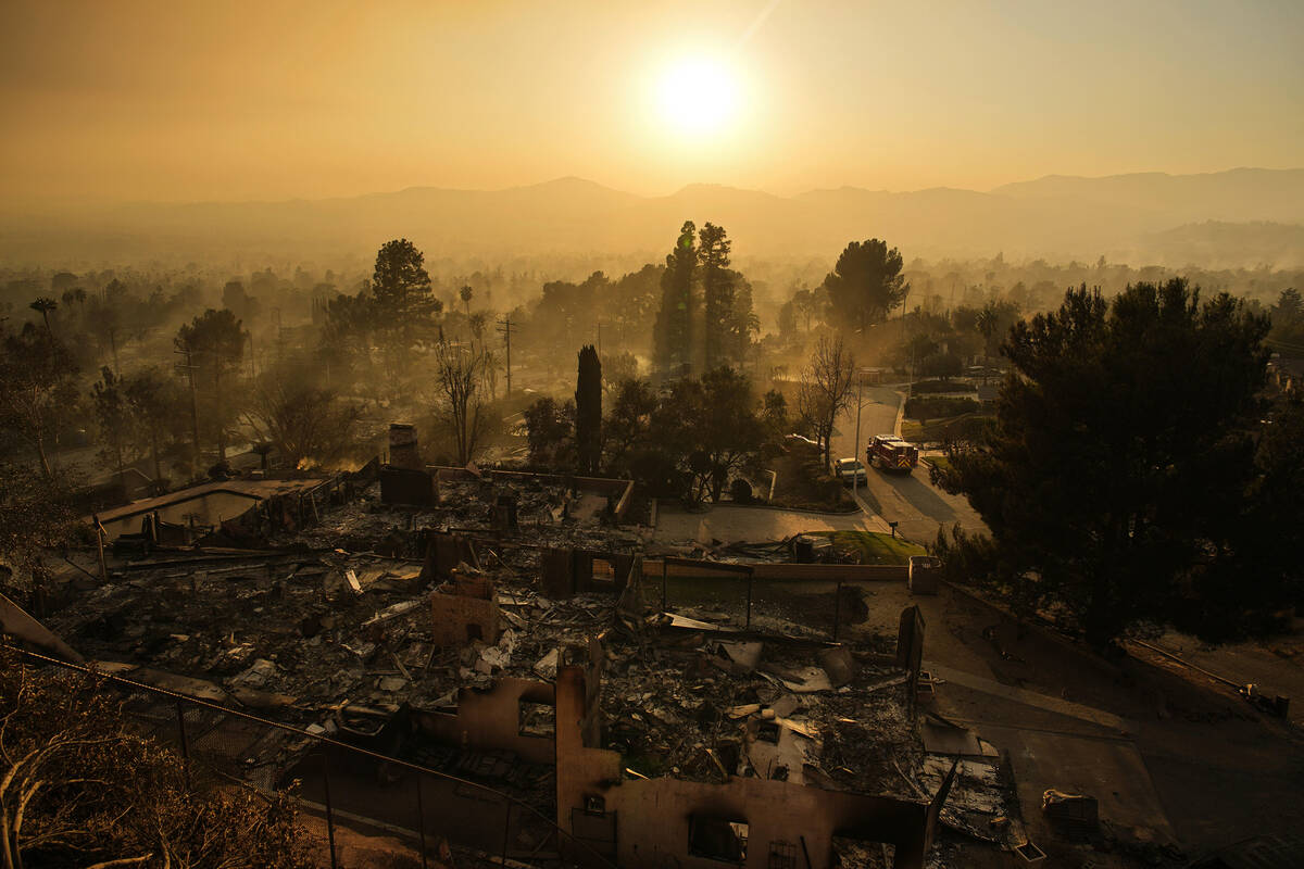 An emergency vehicle drives through a neighborhood devastated by the Eaton Fire, Thursday, Jan. ...