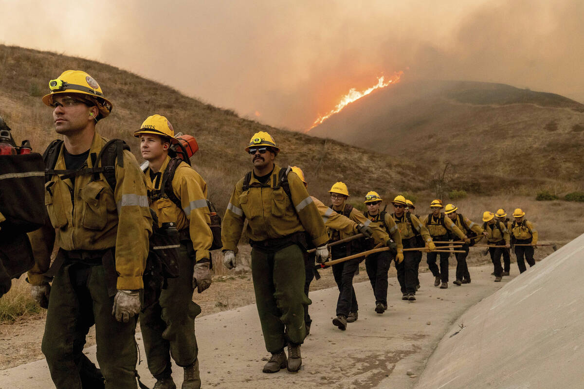 Fire crews walk as they battle the Kenneth Fire in the West Hills section of Los Angeles, Thurs ...
