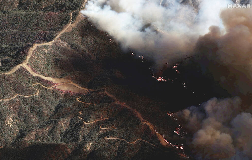 In this photo provide by Maxar Technologies, the Palisades Fire burns south of the Encino Reser ...