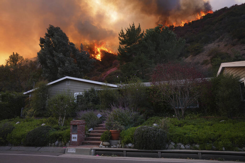 The Palisades Fire burns above a home in Mandeville Canyon, Saturday, Jan. 11, 2025, in Los Ang ...