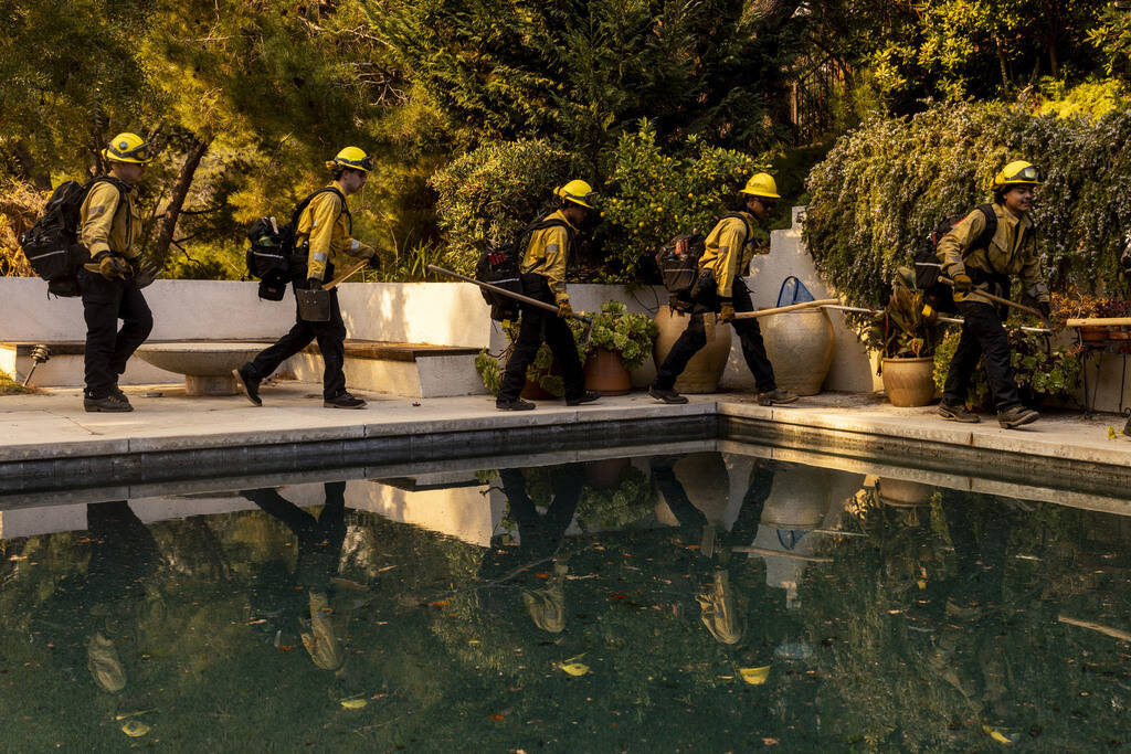 A Cal Fire hand crew walks past a swimming pool toward their next assignment during the Palisad ...