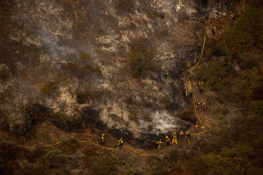A group of firefighters traverse a steep hill while battling the Palisades Fire in the Mandevil ...