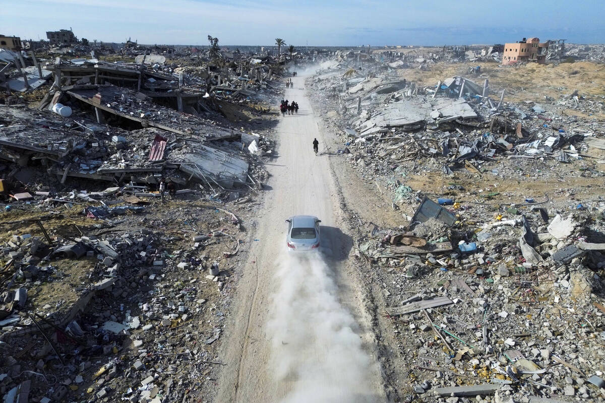 Palestinians walk through the destruction by the Israeli air and ground offensive in Rafah, as ...