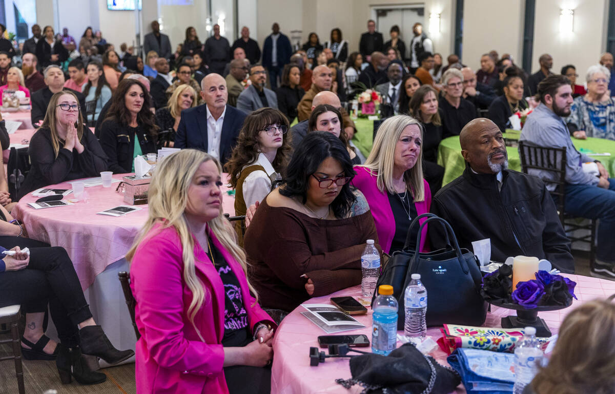 Family members and friends are moved as they watch a slideshow of images during a remembrance g ...