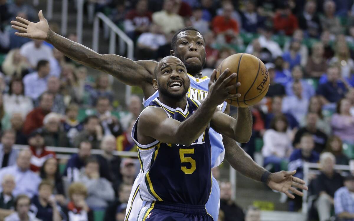 Utah Jazz's John Lucas III (5) goes to the basket as Denver Nuggets' Nate Robinson, rear, defen ...