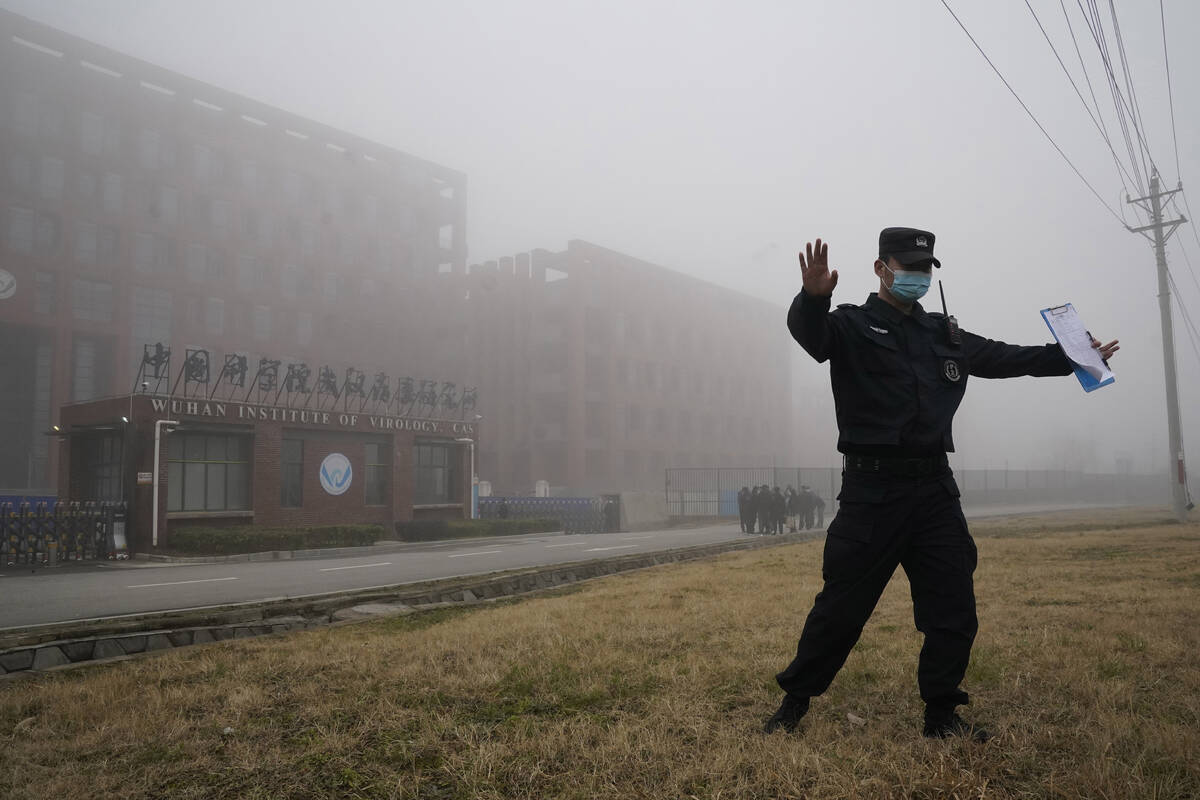 A security person moves journalists away from the Wuhan Institute of Virology after a World Hea ...