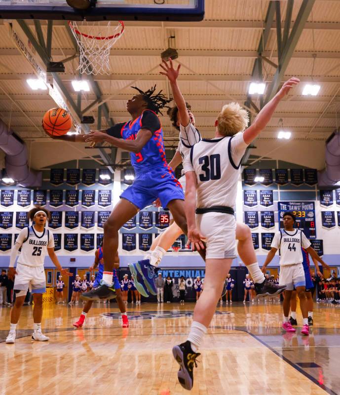 Bishop Gorman guard Ty Johnson (3) lays up the ball under pressure during a basketball game at ...