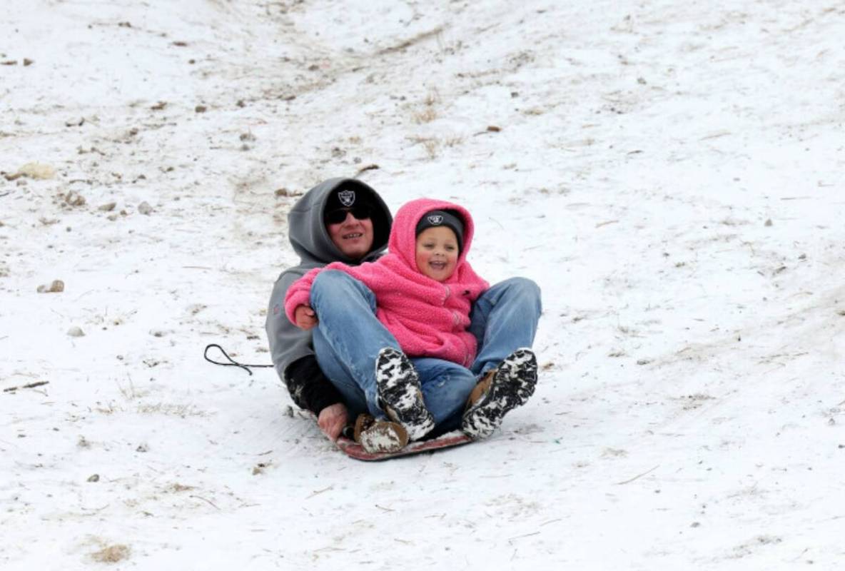 Jason Mellon and his granddaughter Alaunna Mellon, 4, both of Las Vegas, sled in a light snow i ...