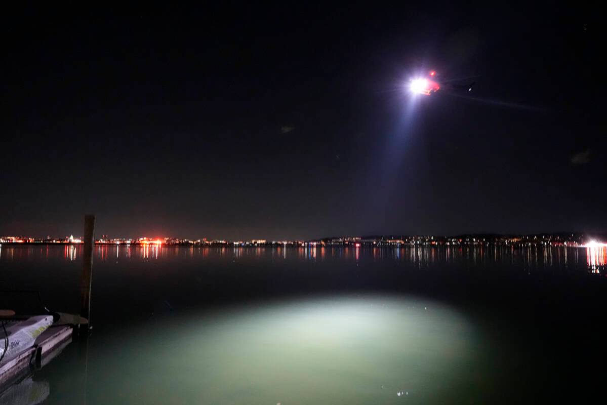 A helicopter uses a spotlight on the Potomac River near Ronald Reagan Washington National Airpo ...