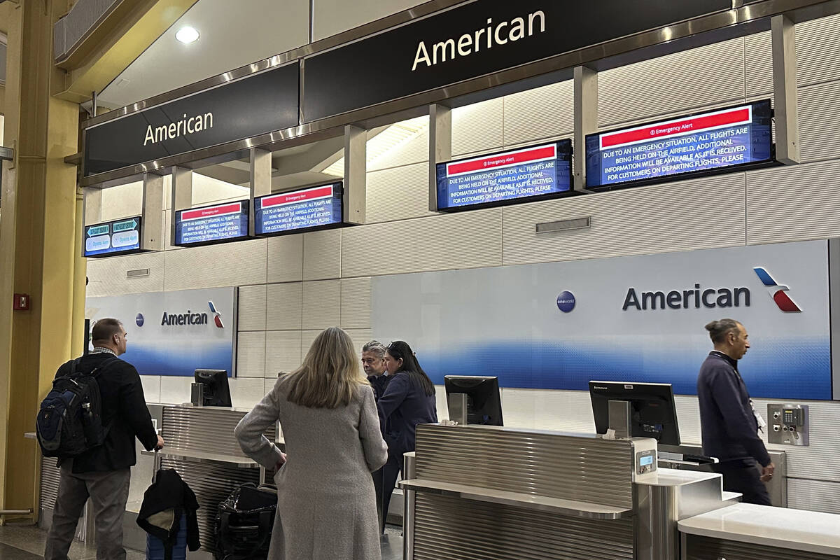 Signs display an "Emergency Alert" above an American Airlines counter in the terminal ...