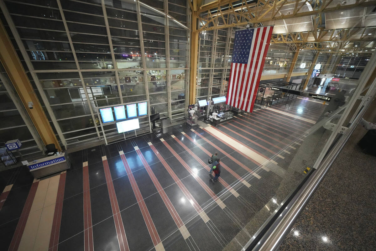 People walk through the virtually empty Ronald Reagan Washington National Airport, Wednesday, J ...