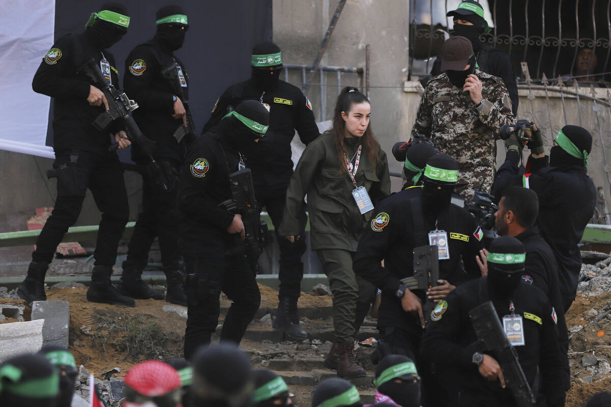 Israeli soldier Agam Berger walks next to masked Islamic Jihad militants as she is handed over ...