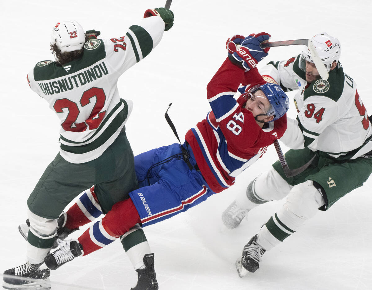 Montreal Canadiens' Lane Hutson (48) is checked by Minnesota Wild's Marat Khusnutdinov (22) and ...