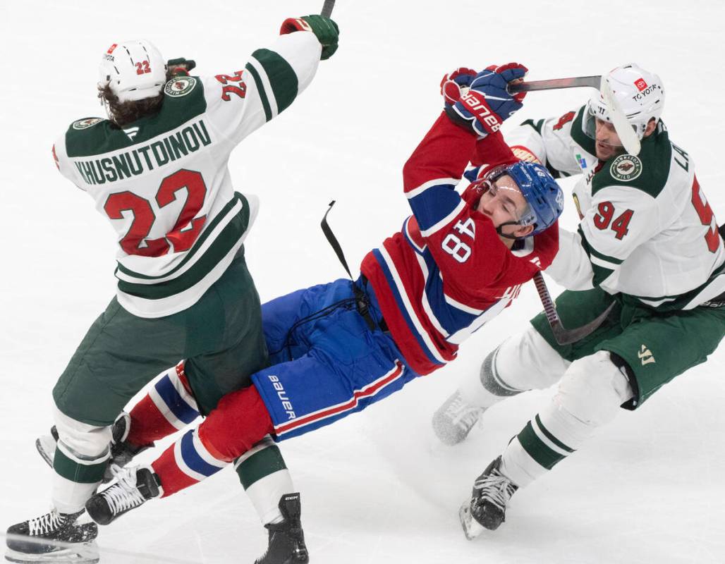 Montreal Canadiens' Lane Hutson (48) is checked by Minnesota Wild's Marat Khusnutdinov (22) and ...