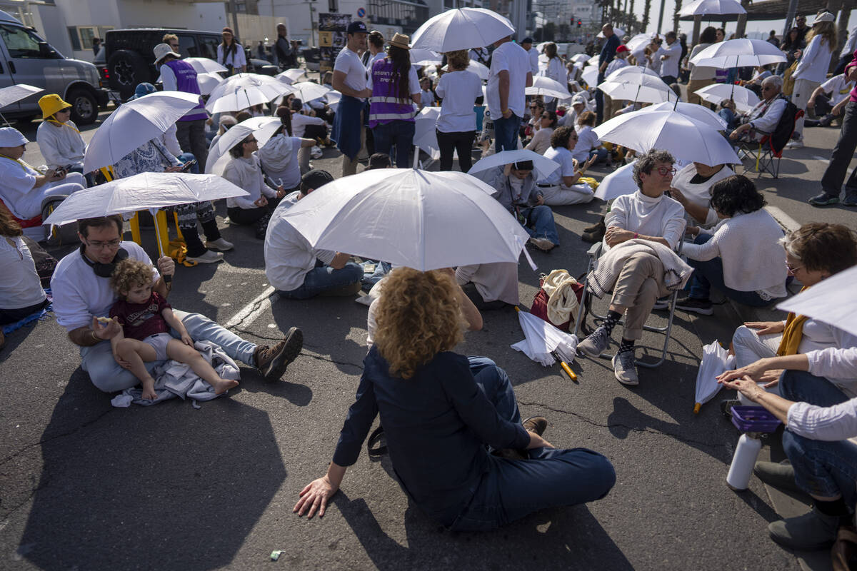 Activists sit on a road with white umbrellas during a protest calling for the release of hostag ...