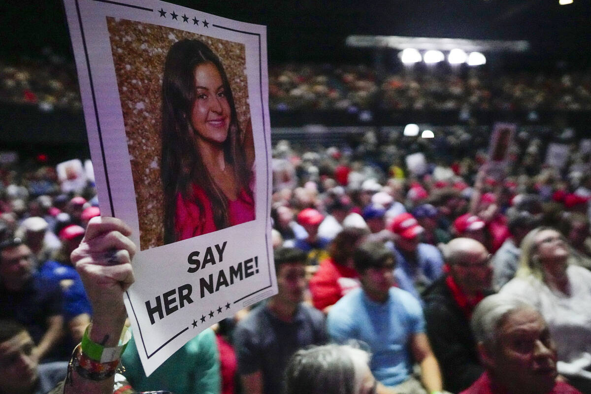 A supporter holds a poster with a photo of Laken Riley before Donald Trump speaks at a campaign ...