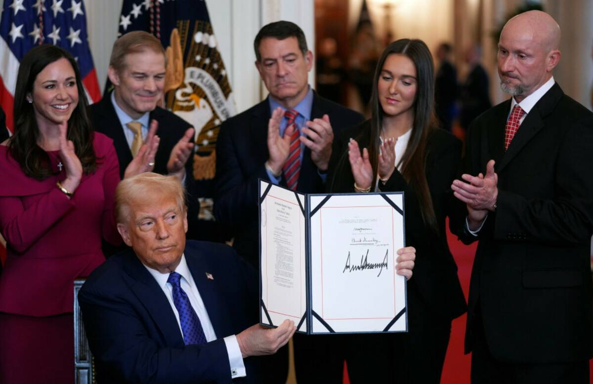 President Donald Trump holds the document after signing the Laken Riley Act during an event in ...