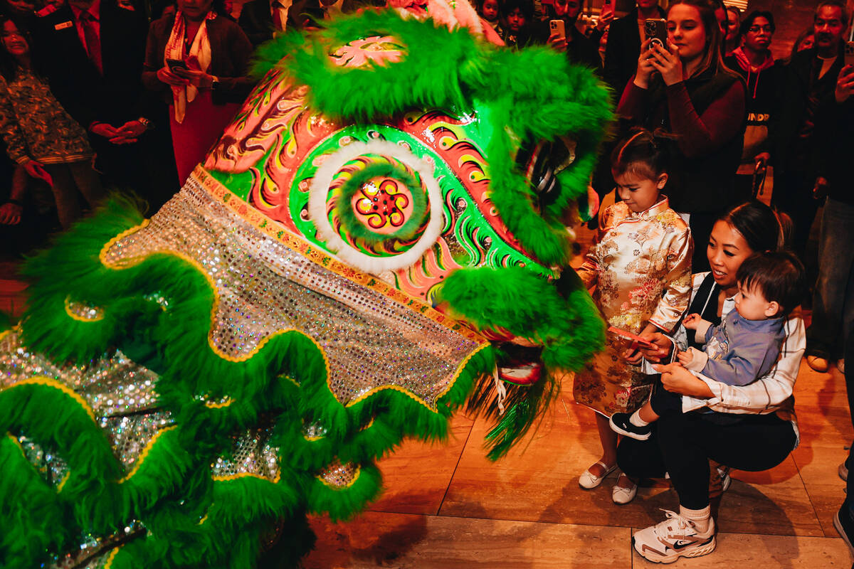 A dancing lion takes money gifts from crowd members during a Lunar New Year parade featuring tr ...