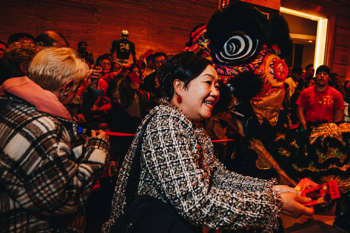 Members of the crowd gift money to dancing lions during a Lunar New Year parade featuring tradi ...