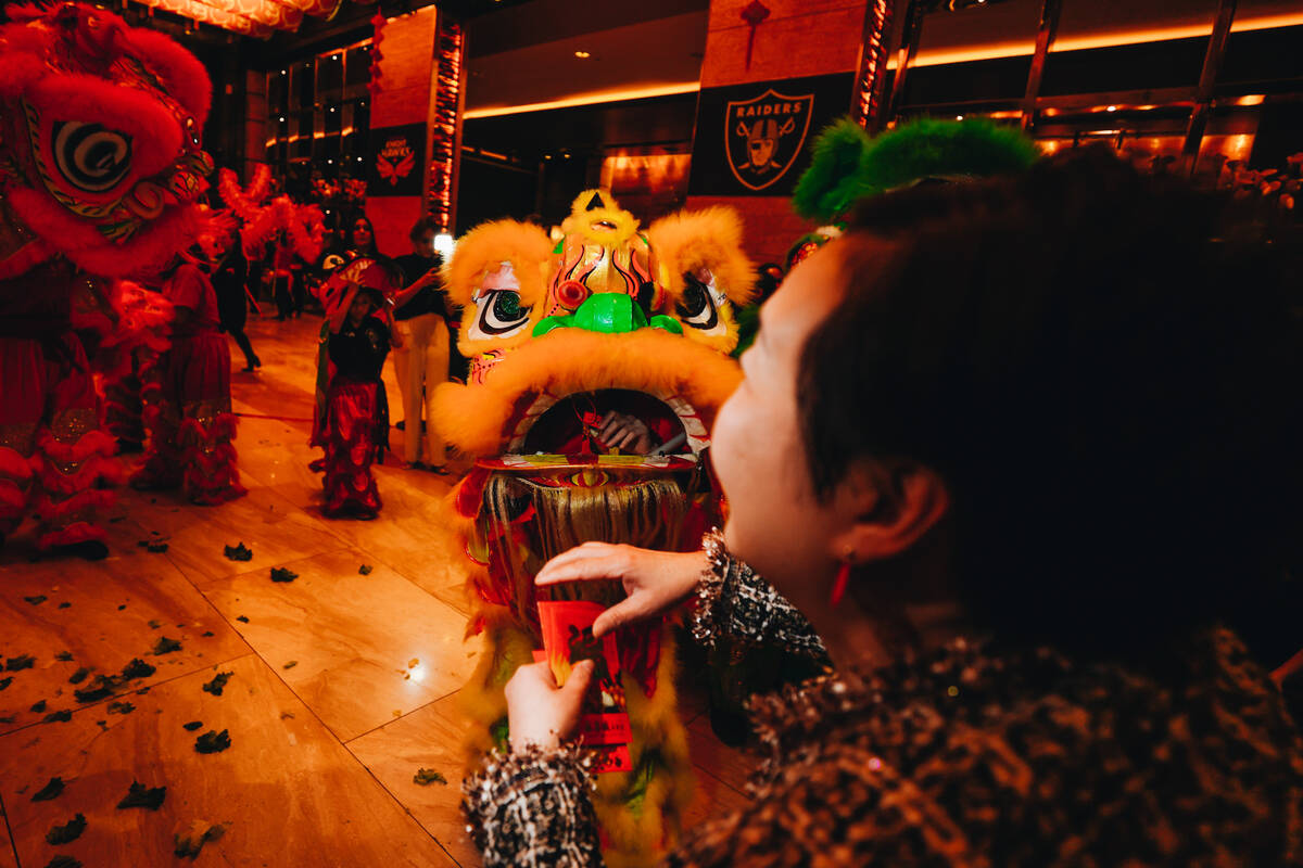 Members of the crowd gift money to dancing lions during a Lunar New Year parade featuring tradi ...