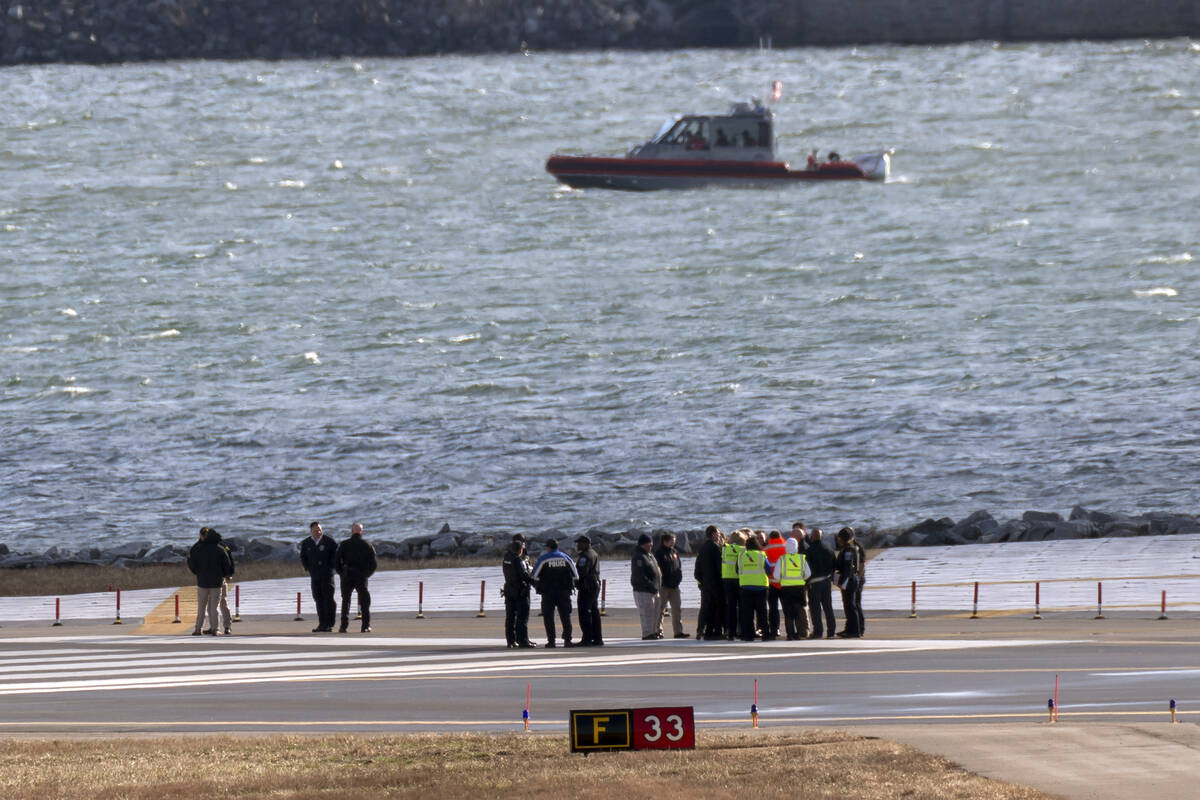 Officials gather at the end of runway 33 near the wreckage site in the Potomac River of a mid-a ...