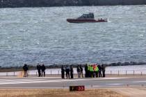 Officials gather at the end of runway 33 near the wreckage site in the Potomac River of a mid-a ...