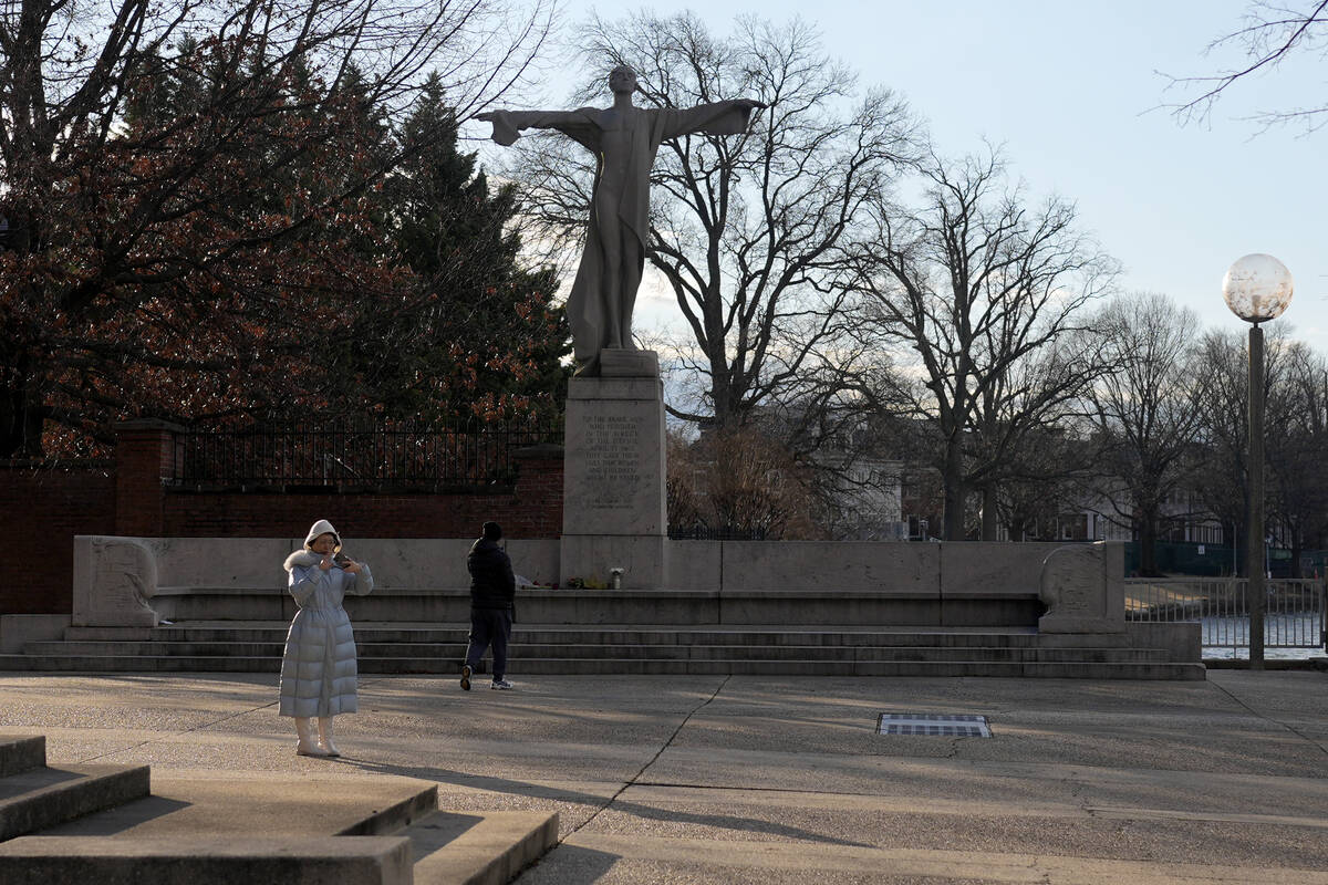 A visitor walks toward flowers and a letter left in memorial to the victims of a mid-air collis ...