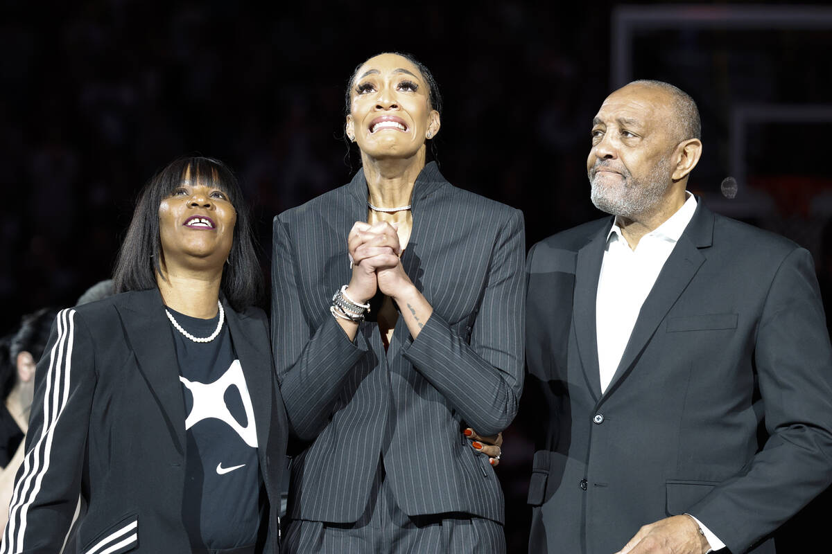 A'ja Wilson, center, stands with her parents Eva and Roscoe Wilson as they watch her number be ...