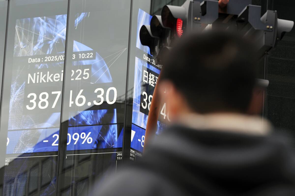 A person walks in front of an electronic stock board showing Japan's Nikkei index at a securiti ...
