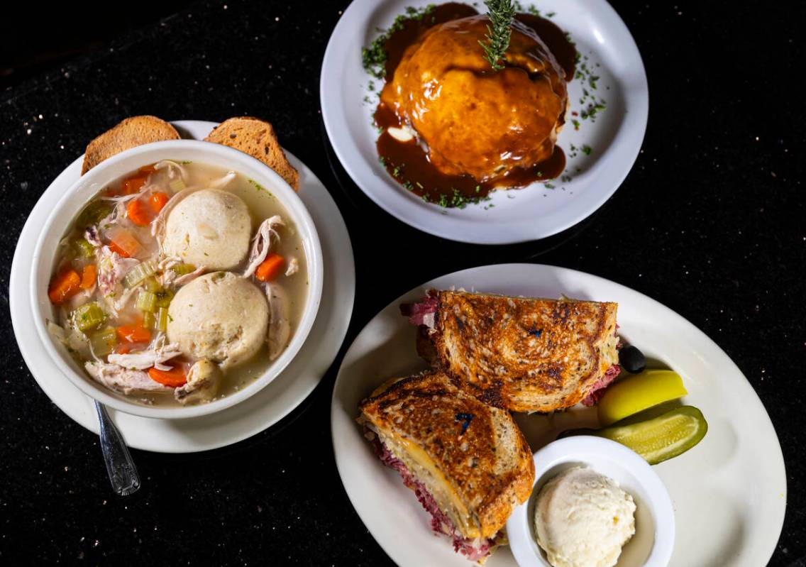 A pastrami Reuben sandwich is pictured alongside a bowl of matzoh ball and chicken noodle soup, ...