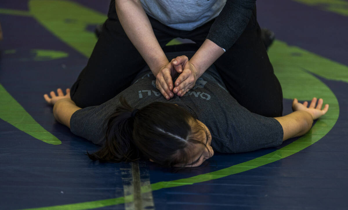Teammates help to stretch and loosen each other up at the start of girl's wrestling practice in ...
