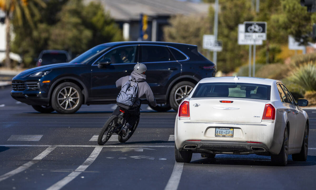 A student rides an e-dirt bike cutting off a car turning onto West Horizon Ridge Parkway from C ...