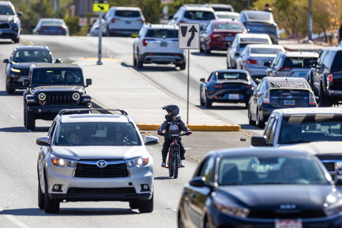A student rides an e-dirt bike between cars on Coronado Center Drive near Coronado High School ...