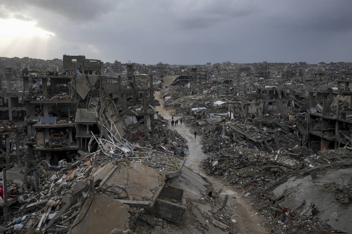 Palestinians walk in the destruction caused by the Israeli air and ground offensive in Jabaliya ...