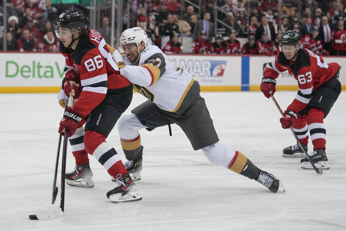New Jersey Devils' Jack Hughes, left, takes shot while Vegas Golden Knights' Shea Theodore chas ...