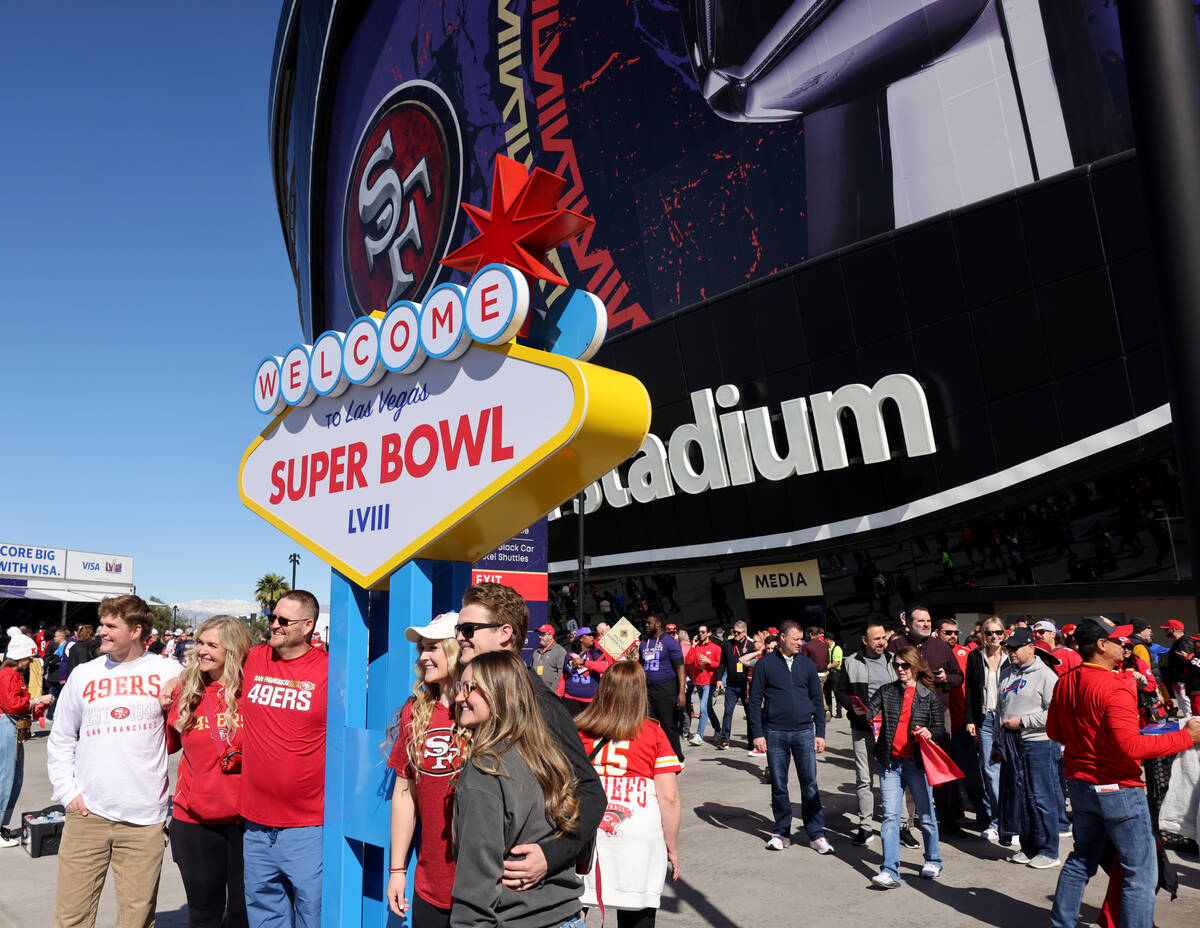 49ers fans pose on one side of a Welcome to Las Vegas sign replica while Chiefs fans pose on th ...