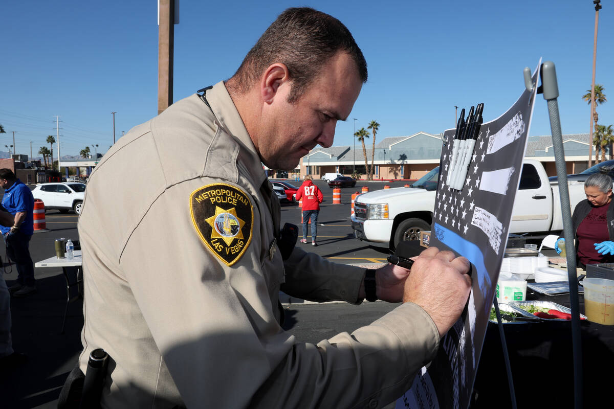 Las Vegas police officer Monty Fetherston signs a banner honoring fallen North Las Vegas Police ...