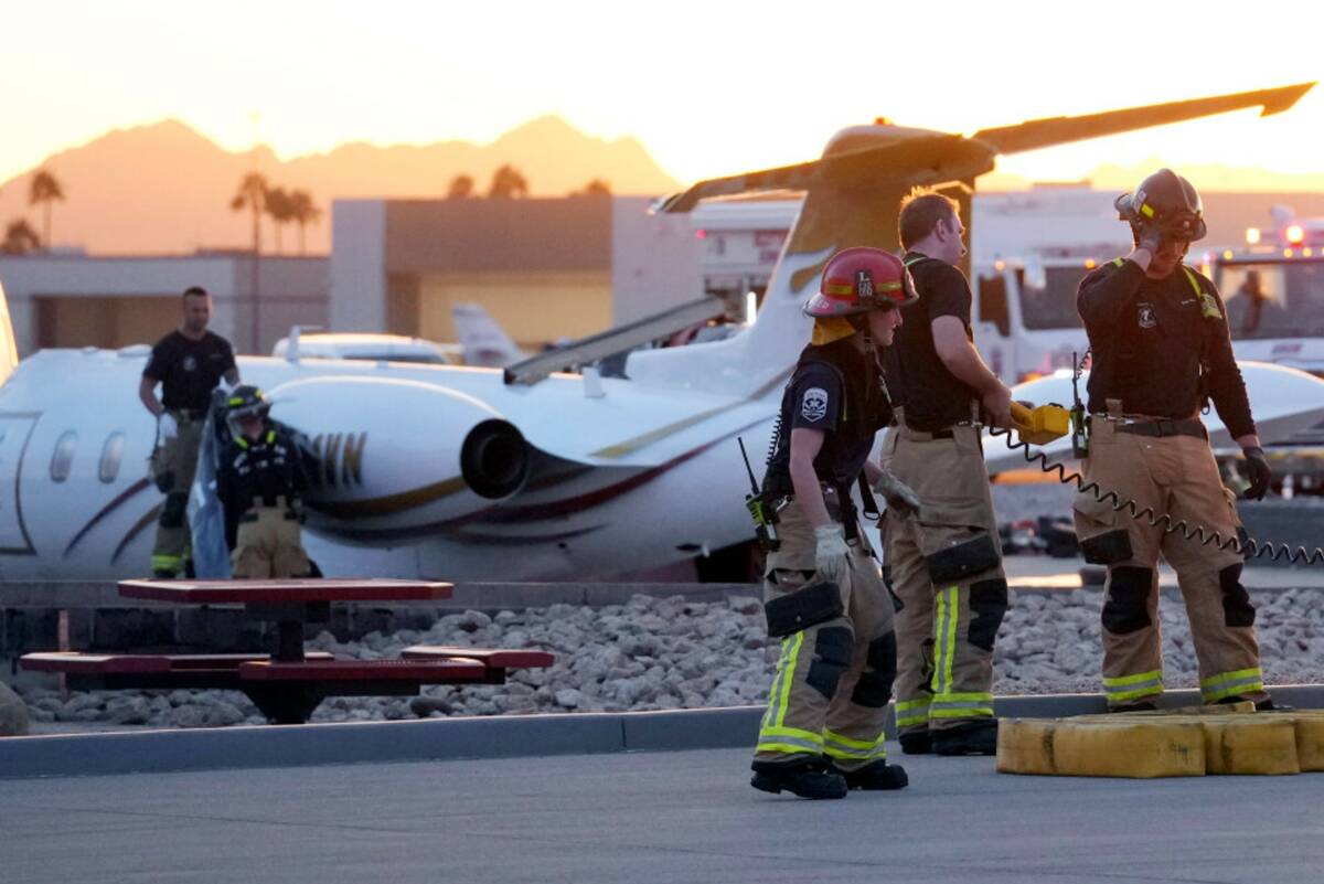 Firefighters work around the site of a crashed Learjet at Scottsdale Airport after it collided ...
