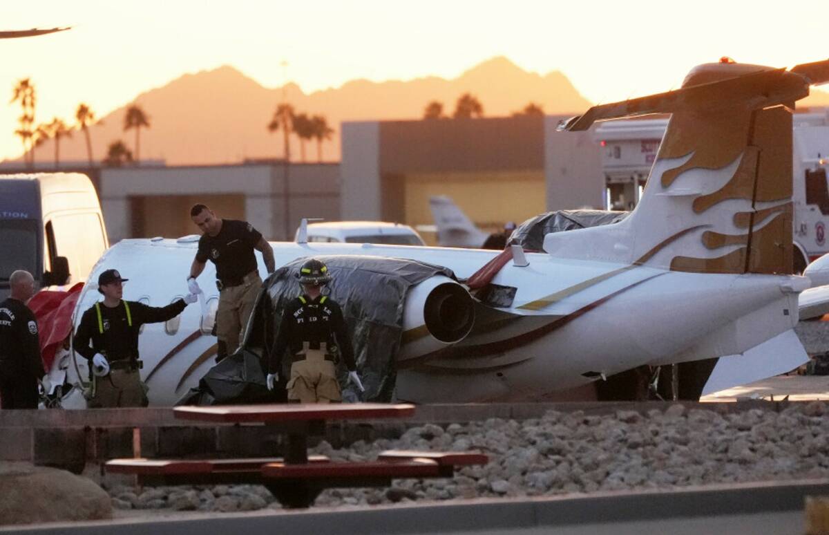 Scottsdale Fire Department firefighters work on a crashed Learjet at Scottsdale Airport after i ...