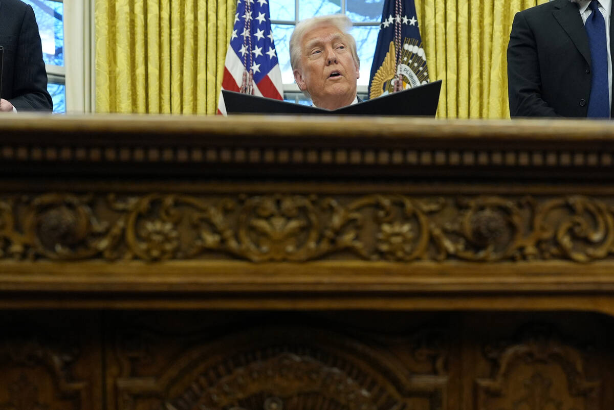 President Donald Trump speaks with reporters as he signs an executive order in the Oval Office ...