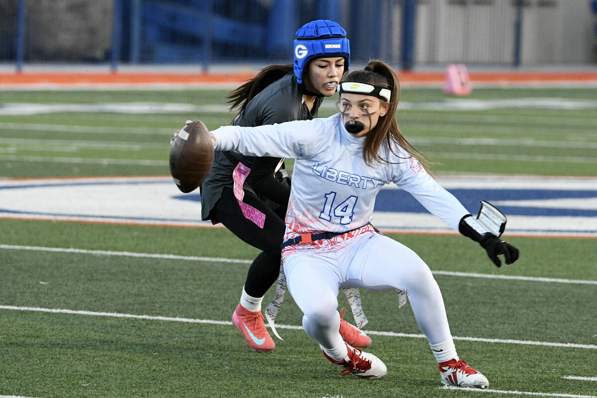 Liberty quarterback Kaylie Phillips is tackled by Bishop Gorman Alana Moore during the 5A flag ...