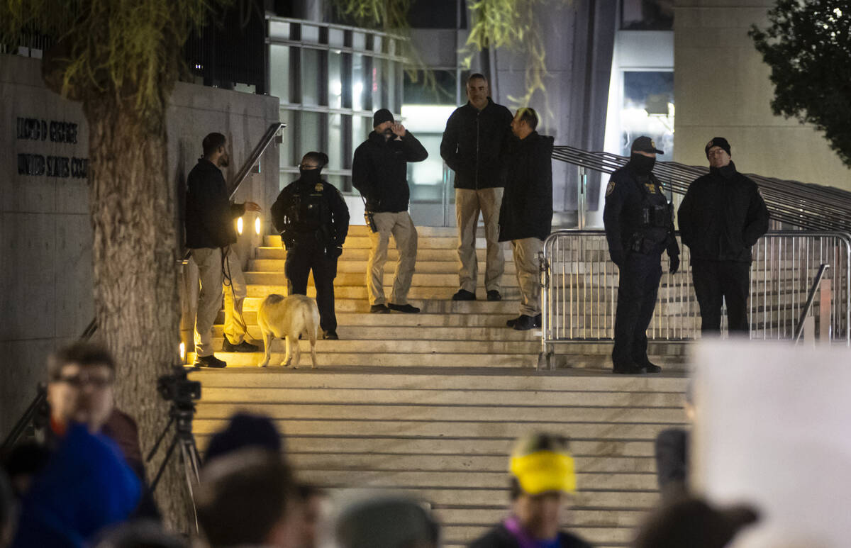 Federal agents stand outside of the Lloyd George U.S. Courthouse as people participate in a ral ...