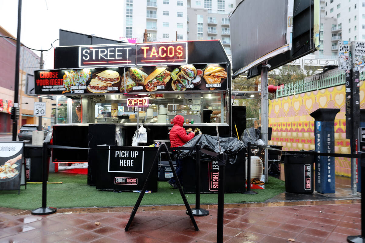A worker covers equipment at a food trailer at Las Vegas Boulevard and Fremont street in Las Ve ...