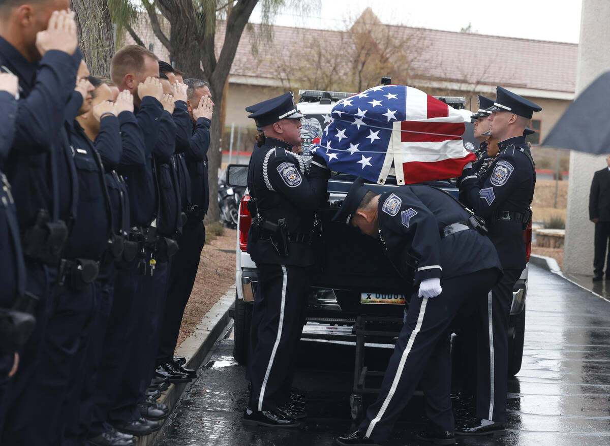 Police officers salute as Honor Guard members load the casket of slain North Las Vegas police o ...