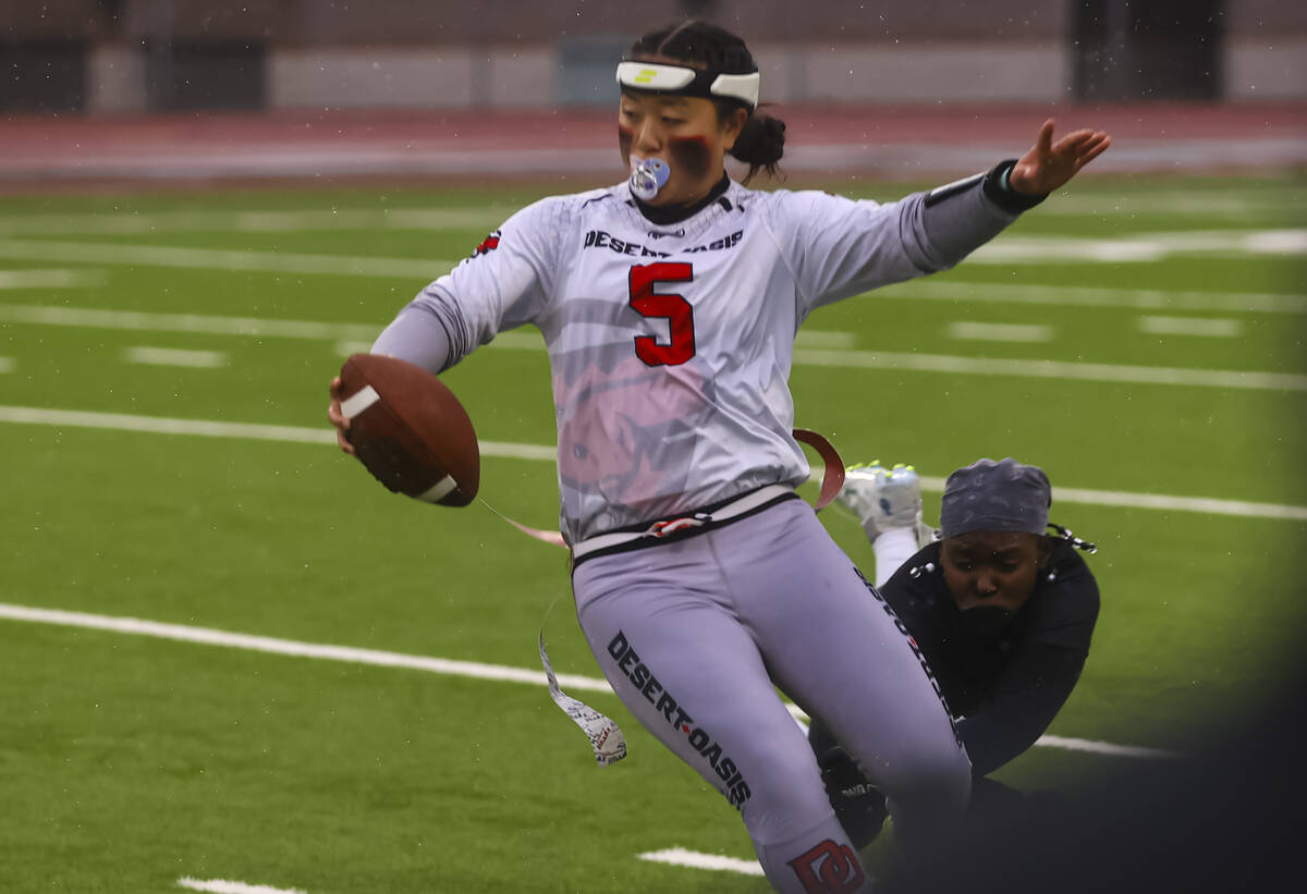 Desert Oasis quarterback Akemi Higa (5) dodges a Shadow Ridge defender while running the ball d ...