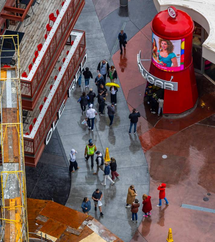 Pedestrians employ umbrellas for the first time in many months as they navigate the Strip while ...