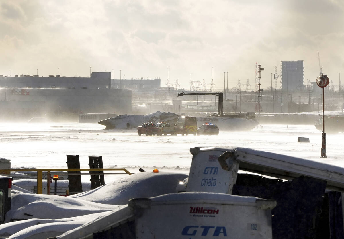 Emergency response vehicles are seen nearby an upside down Delta Air Lines plane, which was hea ...