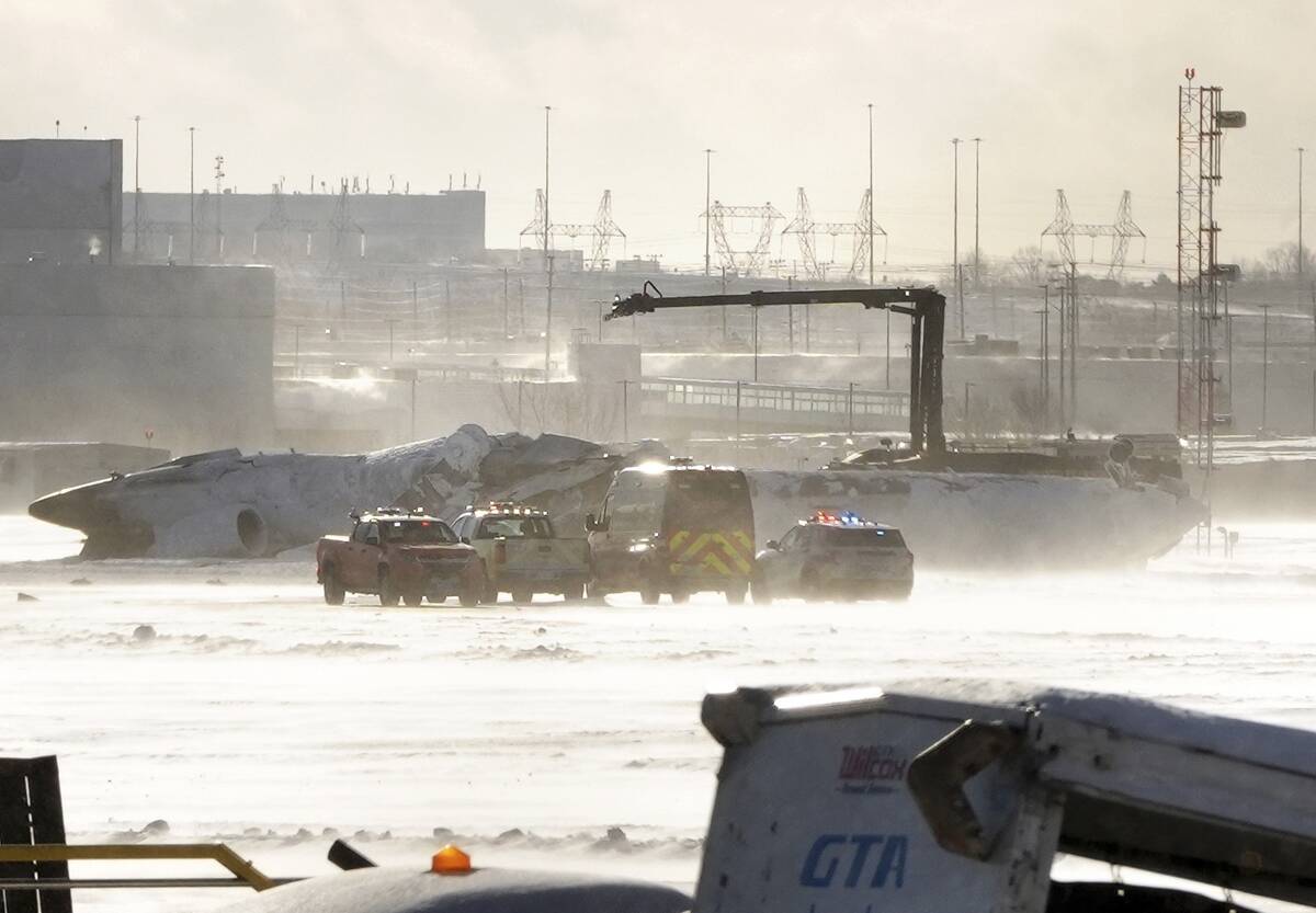 Emergency response vehicles are seen nearby an upside down Delta Air Lines plane, which was hea ...