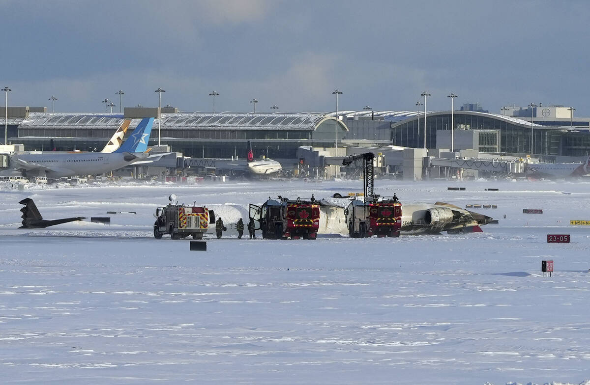 Pearson International Airport firefighters work on an upside down Delta Air Lines plane, which ...
